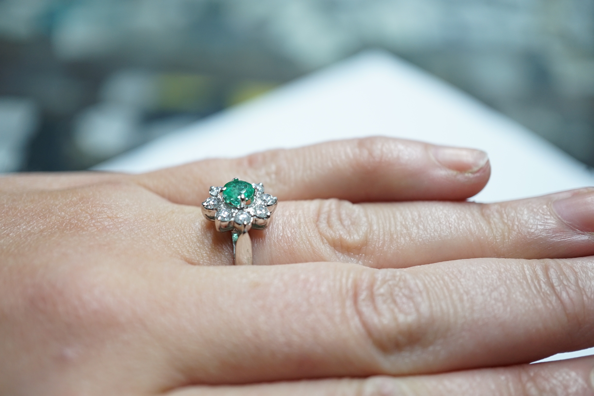 A modern 18k white metal, emerald and diamond set flower head cluster ring, size N, gross weight 4.5 grams.